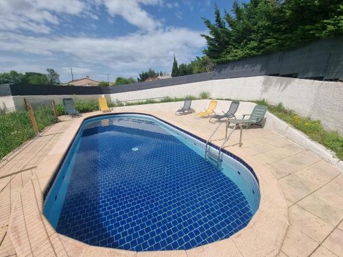 - une piscine bleue avec 2 chaises et une table dans l'établissement Villa avec piscine, à Rocbaron