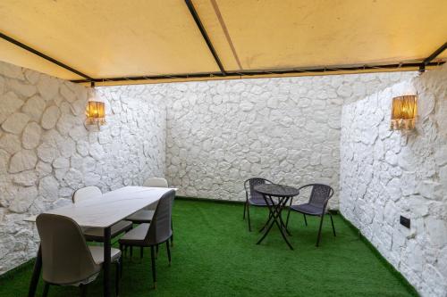 a room with two tables and chairs and green carpet at La Boutique Hôtel - Vue Des Pyramides in Cairo