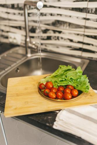 a plate of tomatoes on a cutting board next to a sink at Space Нова стильна квартира біля Центру з ванною in Ternopilʼ
