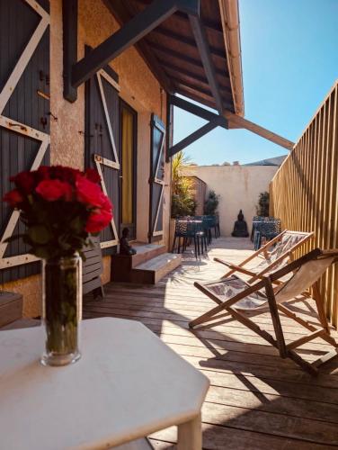 un vase de roses posé sur une table sur une terrasse dans l'établissement LacanOcéane Bed&Breakfast, à Lacanau-Océan
