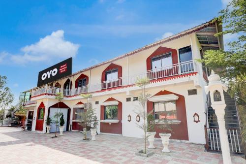 un edificio bianco e rosso con un cartello sopra di Hotel O RamdevGarh Resort a Ahmedabad