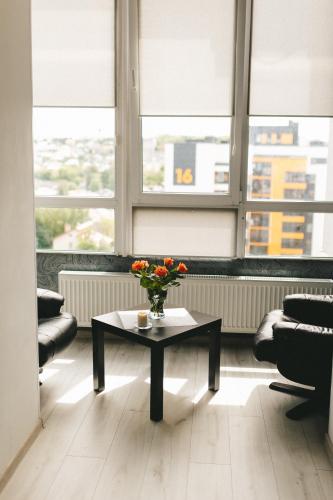 a room with a table with a vase of flowers on it at Space Нова стильна квартира біля Центру з ванною in Ternopilʼ