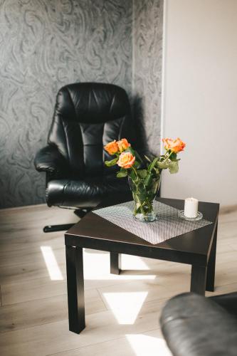 a black chair and a vase with flowers on a table at Space Нова стильна квартира біля Центру з ванною in Ternopilʼ