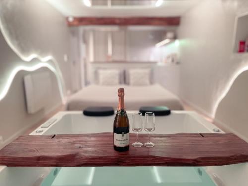 a bottle of wine sitting on a table with two glasses at À la folie - Loft & Spa in Montrevault
