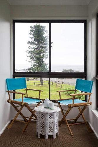 two chairs and a table in front of a window at The Green Dragon, Amazing Views, Ocean Front Reserve in Gerroa