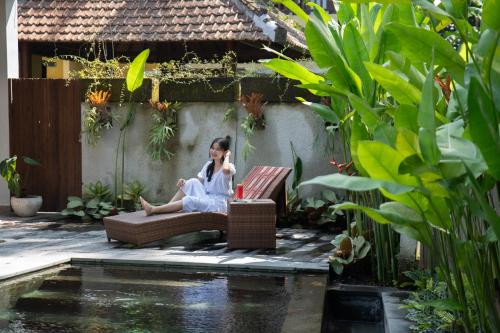 a woman sitting on a couch next to a pond at Villa Rabita in Ubud
