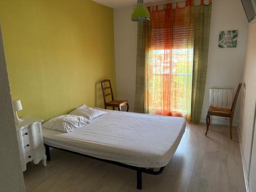 une chambre avec un lit blanc et une fenêtre dans l'établissement T3 centre ville à 8 min à pied avec place parking, à Perpignan