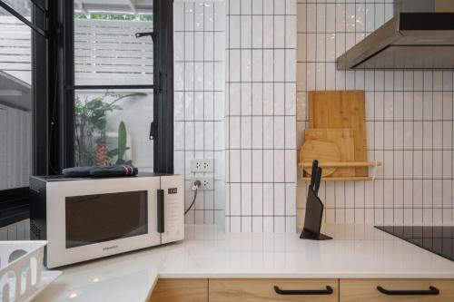 a microwave sitting on top of a kitchen counter at Ayas Retreat - Muji Ekkamai Pool Villa with 4 bedrooms in Khlong Toei