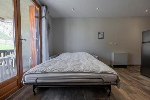 a bed in a room with a large window at Douce Escapade - Balcon - Parking in Jausiers