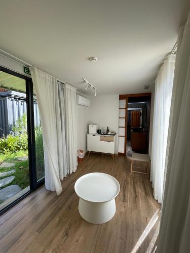 Una sala de estar con una mesa de café blanca frente a las ventanas. en OBOĒ Gardenstē, en Pereybere