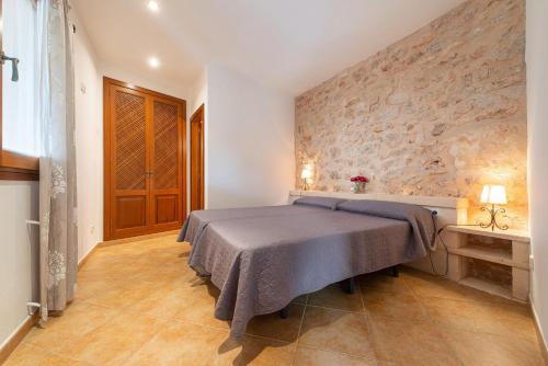 a bedroom with a bed and a stone wall at Cas Batlet in S'Horta