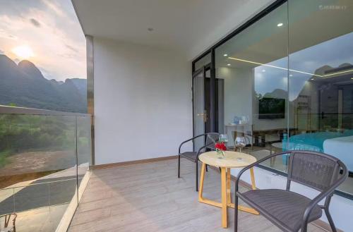 a room with a table and chairs on a balcony at Whispering Retreat in Yangshuo