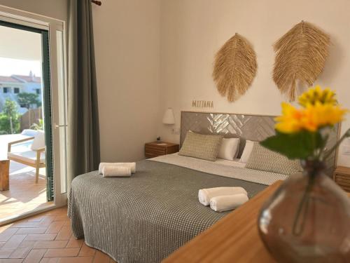 une chambre avec un lit et un vase de fleurs sur une table dans l'établissement Villa Casa Escorxada - A 150m de la playa de arena con piscina privada, à Santo Tomas