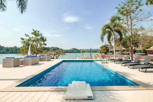 una piscina con sedie e un bacino d'acqua di The Sanctuary Nam Ngum Beach Resort a Vang Vieng