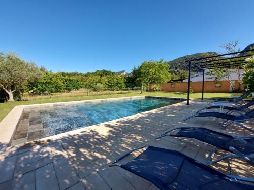 - une piscine avec deux chaises bleues à côté dans l'établissement En Provence, Luberon, villa avec piscine à Maubec, à Maubec