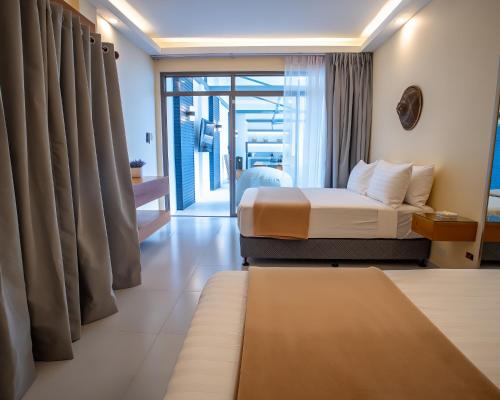 a hotel room with a bed and a balcony at Villa Kalachuchi Bohol in Panglao