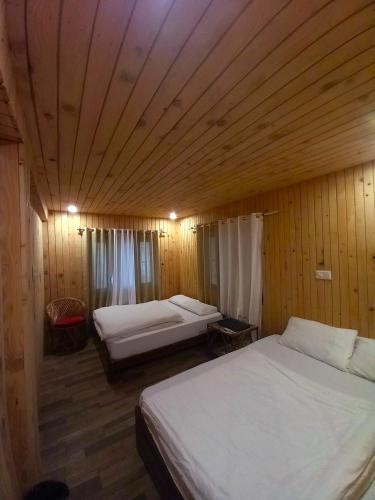 a bedroom with two beds and a wooden ceiling at Hotel Himalayan in Madheso