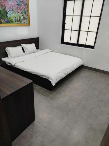 a bedroom with a bed with white sheets and a window at Tony Villa Homestay Ba Vì in Ba Vì