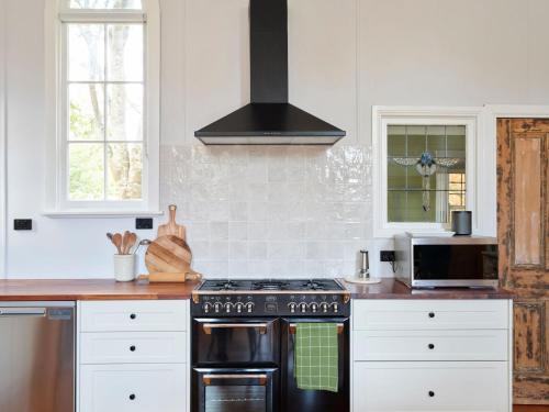 a kitchen with white cabinets and a stove top oven at The Old Trentham Church in Trentham