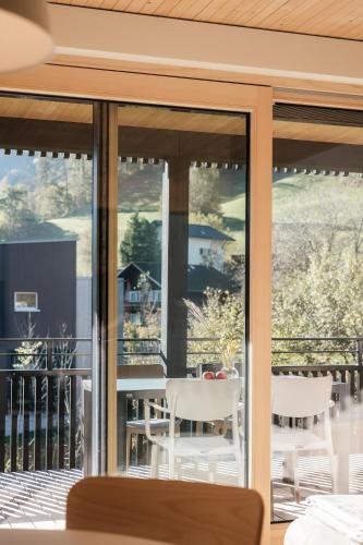 a balcony with white chairs and a table on a patio at AlpenApart Montafon - Alti Saga in Tschagguns