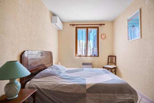 ein Schlafzimmer mit einem Bett und einer Lampe und einem Fenster in der Unterkunft Jolie Maison Proche De La Plage in La Londe-les-Maures