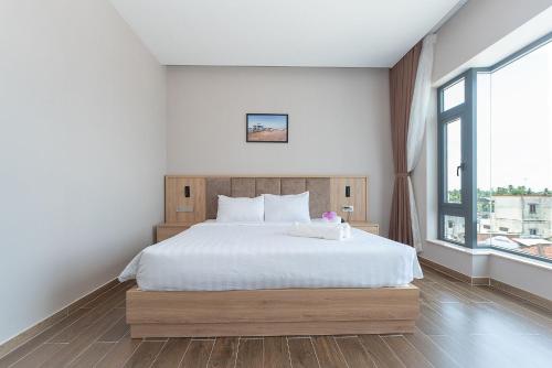 a bedroom with a white bed and a large window at Bamboo Riverside Boutique Hotel in Ben Tre
