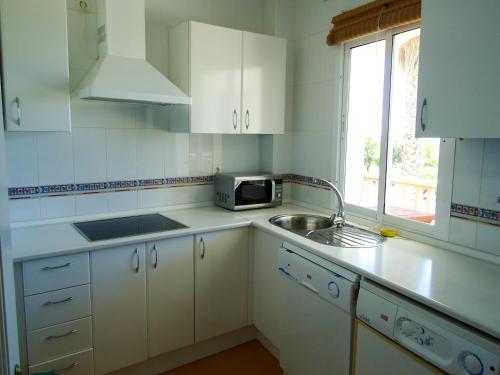 a white kitchen with a sink and a microwave at Vista al Mar con Terraza - Costa Ballena Apartamento primera linea de playa in Costa Ballena
