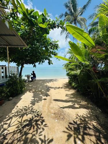 two people sitting on a bench on the beach at Dream Villa Beachfront Sunset in Ban Bang Po