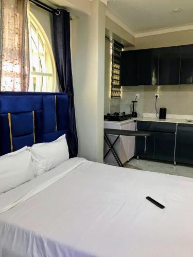 a bedroom with a white bed and a kitchen at Yazmin's Bright Studio with Fast Wi-Fi & Parking in Kampala