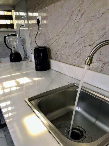 a kitchen sink with water coming out of a faucet at Yazmin's Bright Studio with Fast Wi-Fi & Parking in Kampala
