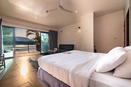 una camera da letto con un grande letto bianco e un balcone di The Sanctuary Nam Ngum Beach Resort a Vang Vieng