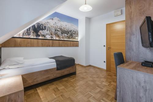 a bedroom with a bed and a tv and a desk at Pension Török in Lesce