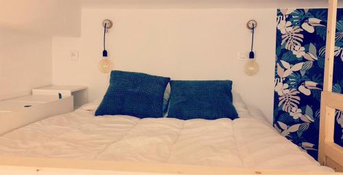 - un lit avec 2 oreillers bleus dans une chambre dans l'établissement Studio à 2 pas du Moulin Rouge, à Paris