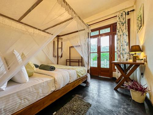 a bedroom with a canopy bed and a window at CAO Ella in Ella
