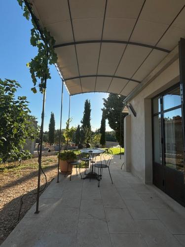 a patio with a table and chairs under awning at Brin d'Olivier en Luberon in Gargas