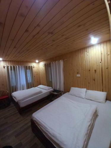 two beds in a room with wooden walls and ceilings at Hotel Himalayan in Madheso