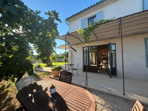 a patio with a wooden table and chairs in front of a house at Brin d'Olivier en Luberon in Gargas