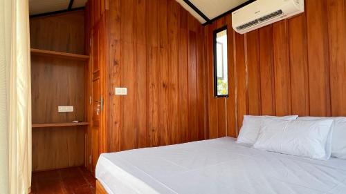 a bedroom with a white bed in a wooden wall at Alpine Zenith - Luxury Wooden Cottages in Meppādi
