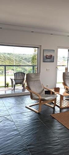 a living room with two chairs and a large window at Zambujeiraseahouse - 100m da praia in Zambujeira do Mar