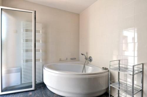 La grande salle de bains blanche est pourvue d'une baignoire et d'une douche. dans l'établissement Villa Sea View at Eden Roc Hotel, Pool, Ocean, Beach, BBQ, à Vallauris