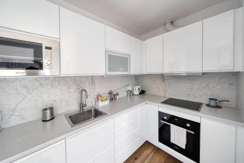 a white kitchen with white cabinets and a sink at Apartments Trnovo in Ljubljana
