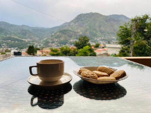 een kop koffie en een kom koekjes op een tafel bij Sapphire Lodges in Muzaffarabad