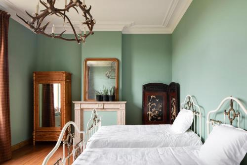 a bedroom with two beds and a mirror at Landhuis uit 1899 met grote tuin in Ellezelles