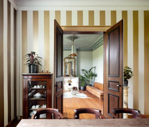 a dining room with a table and chairs and a mirror at Landhuis uit 1899 met grote tuin in Ellezelles