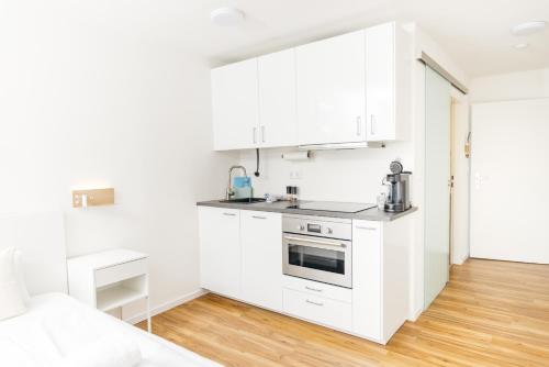 a white kitchen with white cabinets and a stove at Rosenalm Scheidegg in Scheidegg