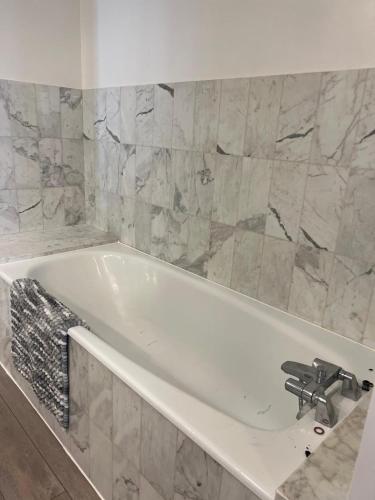 La salle de bains est pourvue d'une baignoire blanche et de murs en marbre. dans l'établissement lieu cosy, Vieux Port à pied, à La Rochelle