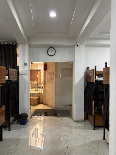 a room with a clock on a wall with a door at aaram ac dormitory in Ahmedabad