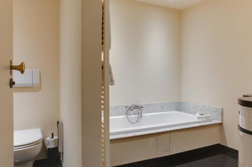 a bathroom with a bath tub and a toilet at Hotel De Witte Lelie -Small Luxury Hotels of the World in Antwerp