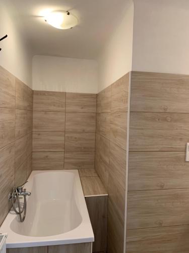 a bathroom with a white tub and wooden walls at Panda apartman in Esztergom
