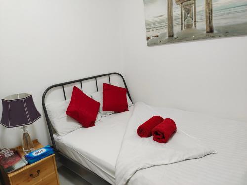 Una cama blanca con dos almohadas rojas. en Bet El Cozy & Comfy Room 4, en Parkside